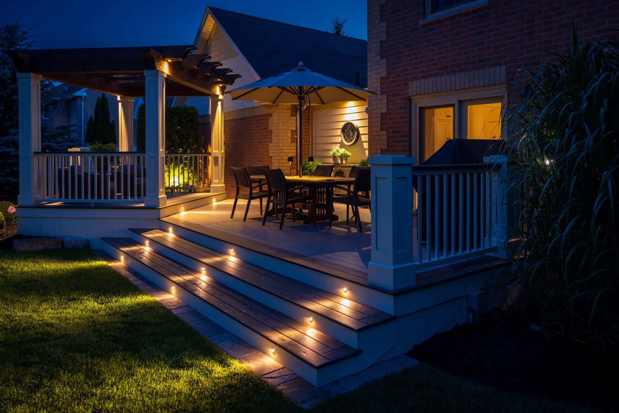 photo of a custom deck at night with traditional pergola and in-step deck lighting