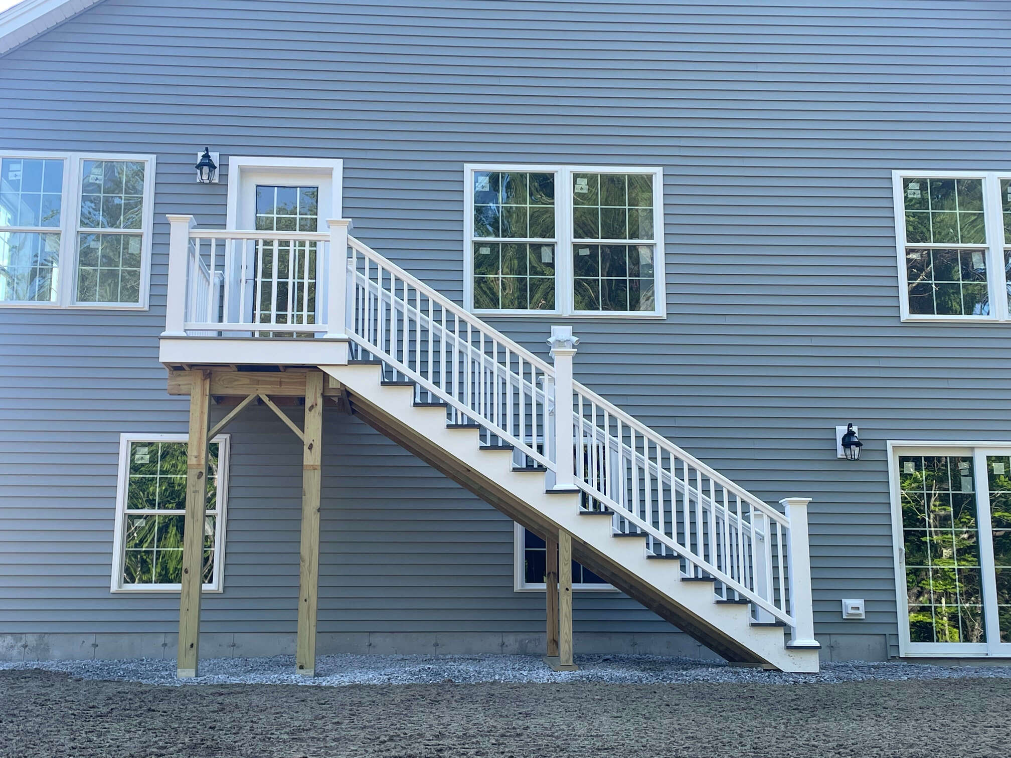 photo of a home exterior project with new siding, new windows, and steps leading to a second-story platform and door