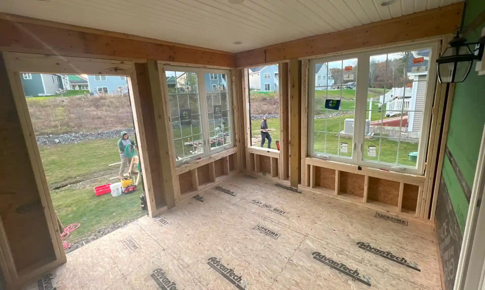 Crew building a covered porch with windows and solid roof 