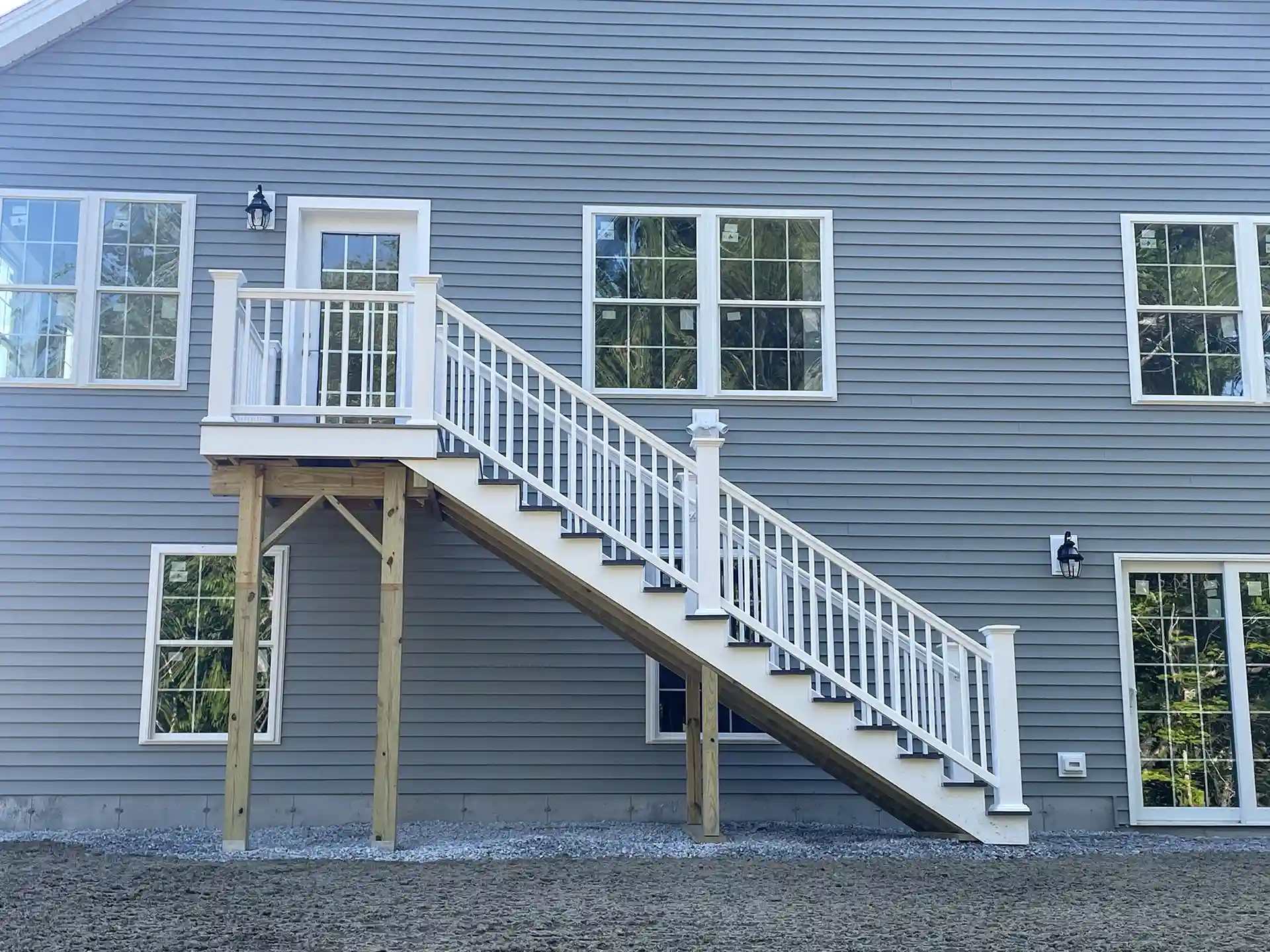 photo of a home exterior project with new siding, new windows, and steps leading to a second-story platform and door - Siding Contractors - Window Replacement Services in Dover NH