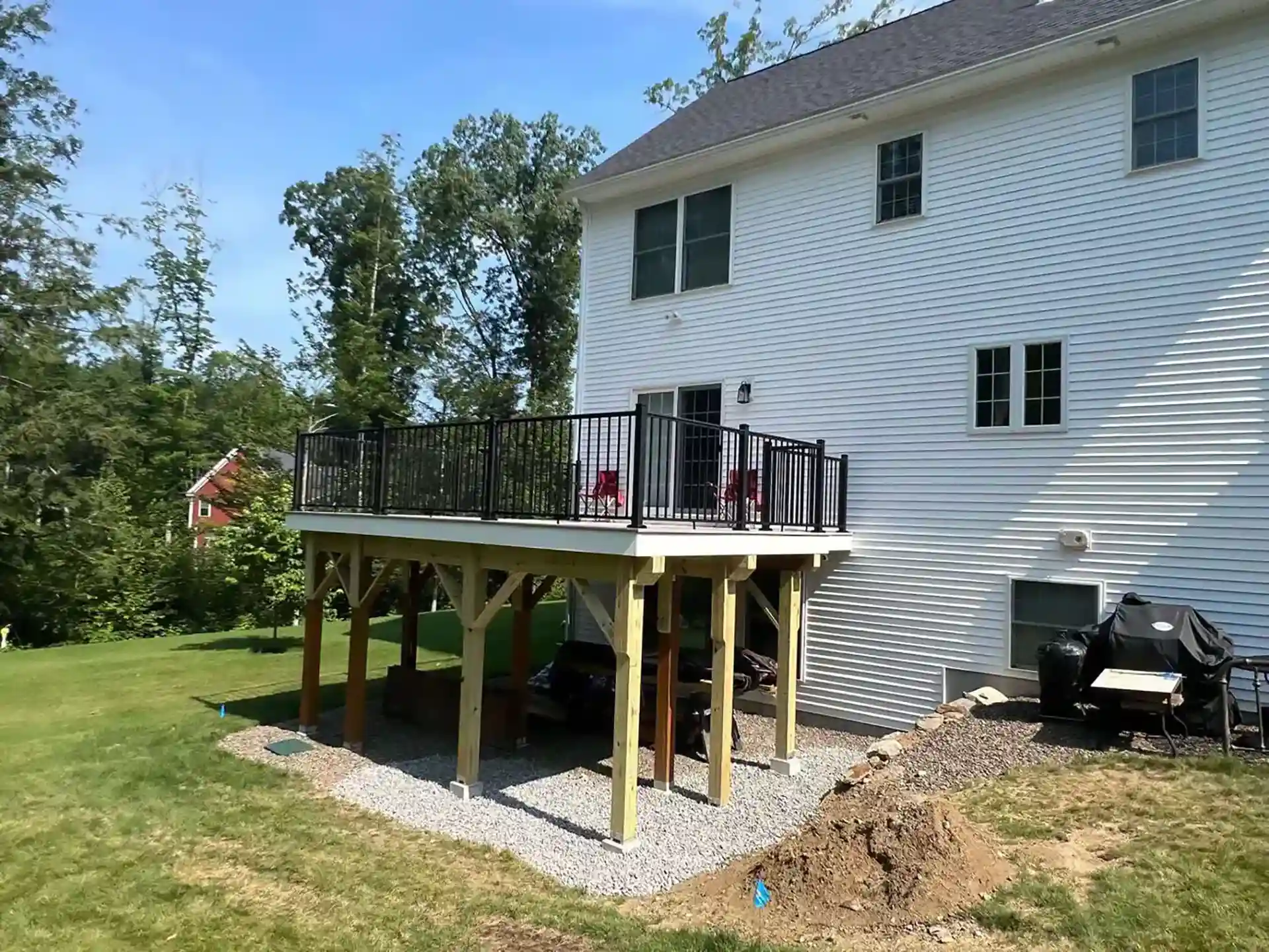 Photo of a raised backyard composite deck with black railings and open under-deck storage area.
