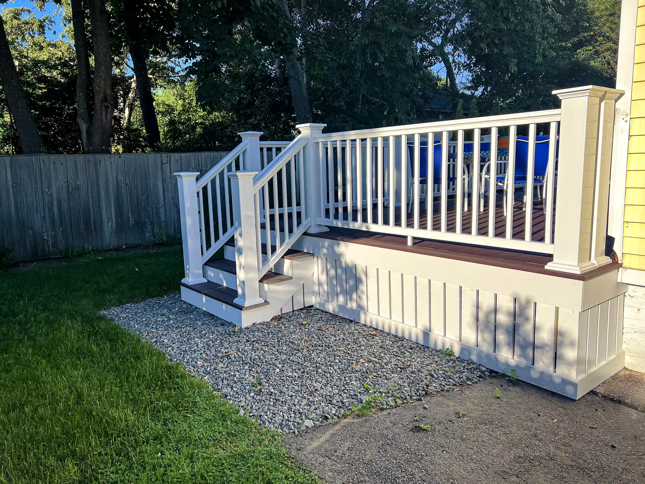 Photo of a composite deck with skirting, deck railing, and deck steps.